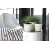 A white chair and two potted plants on a white cylindrical table. Produktbild-Vorschau