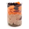 A glass jar filled with layers of food ingredients, including seeds, meat, shredded carrots, and dried fruit. Produktbild-Vorschau