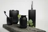 A set of black bathroom accessories arranged on a piece of wood. Produktbild-Vorschau