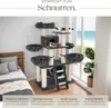 A cat tree with multiple levels and platforms, set up indoors with a bed and window in the background. Náhled obrázku produktu