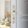 A close-up of a silver door handle on a white door, with a blurred interior scene in the background. Produktbild-Vorschau