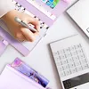 A person's hand is writing in a purple binder notebook next to a white calculator and a purple patterned pencil case. Voir les images du produit