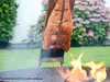 A large salmon fillet is being cooked over an open fire on a wooden board. Voir les images du produit
