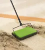 A green carpet sweeper is being used to clean a dirty carpet. Produktbild-Vorschau