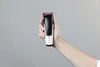 A hand holding a hair clipper against a plain background. Podgląd zdjęcia produktu