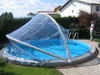 A person is using a pool cover over a round swimming pool in a backyard setting. Náhled obrázku produktu