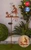 A garden stake with a rain gauge and solar LED light, decorated with a silhouette of a girl watering flowers, is placed in a garden setting. Anteprima dell’immagine prodotto