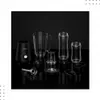 A black stand mixer base with various clear blender attachments and cups arranged on a reflective black surface against a black background. Podgląd zdjęcia produktu