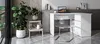 A modern home office setup with a white corner desk, a clear chair, and several potted plants. Produktbild-Vorschau
