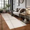 A modern living room with a long rug, a sofa with pillows, and a side table with a lamp and a teapot. Produktbild-Vorschau