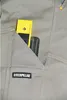 Close-up of a work pant pocket with a yellow level and a black tool handle inserted. Produktbild-Vorschau