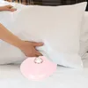 A person is making a bed, placing a pillow on a white sheet. A pink heart-shaped alarm clock is on the bed. Podgląd zdjęcia produktu