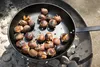Chestnuts being roasted in a pan over coals. Produktbild-Vorschau