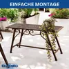 A metal garden bench with decorative scrollwork sits on a patio, surrounded by potted plants. Náhľad obrázku produktu