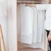 A person's arm is seen reaching for a white garment bag hanging in a closet. Produktbild-Vorschau