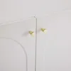 A close-up view of two gold knobs on white cabinet doors with an arched design. Podgląd zdjęcia produktu
