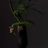 A black vase with a floral arrangement against a dark background. Náhled obrázku produktu