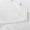 A close-up view of white waffle-weave fabric, likely from a bathrobe or similar textile. Náhled obrázku produktu