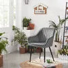 A gray velvet chair with black metal legs is placed in a room with several potted plants and a decorative wall sign. Produktbild-Vorschau