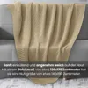 A knitted blanket draped over a sofa. Náhled obrázku produktu