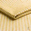 A close-up view of a folded yellow and white patterned fabric. Produktbild-Vorschau