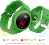 A green smartwatch is displayed with its screen showing a heart rate graph and the number 085. The back of another smartwatch is also visible, showing a green light. Below the watches are icons representing features like step counting, calorie burning, hea Produktbild-Vorschau