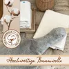 A close-up view of folded white cloths and a gray plush toy, with cotton branches and text overlays. Produktbild-Vorschau