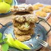 A stack of apple scones dusted with powdered sugar, served on a dark plate with sliced apples and mint leaves. Produktbild-Vorschau