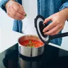A person is adding herbs to a pot of tomato sauce on an induction stove. Voir les images du produit