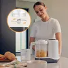 A woman is using a baby food maker in a kitchen setting. Produktbild-Vorschau