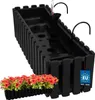 A black plastic planter box with a self-watering system and a small tray of red flowers in front of it. Náhľad obrázku produktu