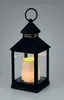 A black metal lantern with a lit LED candle inside, set against a plain light gray background. Náhled obrázku produktu