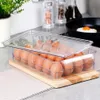 A clear plastic egg container filled with brown eggs, placed on a wooden board on a kitchen counter. Náhled obrázku produktu