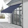 A dark blue awning is extended over a large window on a white building, with a wooden deck in the foreground. Anteprima dell’immagine prodotto