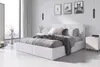 A white upholstered bed with bedding and a nightstand in a minimalist bedroom. Produktbild-Vorschau
