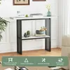 A narrow console table with a marble-look top and black metal frame, decorated with plants and books, set against a white wall with molding. Produktbild-Vorschau