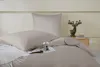 A neatly made bed with taupe bedding and a decorative deer figurine on a nightstand in the background. Podgląd zdjęcia produktu
