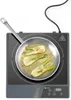 A close-up, top-down view of an induction cooker with a frying pan containing fennel being cooked on it. Náhled obrázku produktu