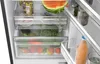 Inside view of an open refrigerator showing drawers filled with fruits and vegetables, and a bottle of juice on the door shelf. Produktbild-Vorschau