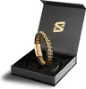 A black and gold leather bracelet is displayed in its open black gift box with a gold logo on the inside lid. Anteprima dell’immagine prodotto
