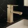 A close-up shot of a gold-colored faucet on a black marble countertop next to a white sink. Náhľad obrázku produktu