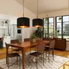 A dining room with a wooden table and chairs, illuminated by two black pendant lights. Anteprima dell’immagine prodotto