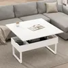 A white lift-top coffee table is shown in a living room setting, with a sectional sofa in the background. Podgląd zdjęcia produktu