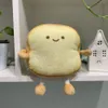 A plush toy shaped like a slice of toast sits on a shelf next to a small decorative house. Náhľad obrázku produktu