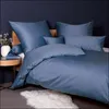 A neatly made bed with blue bedding and pillows, next to a small wooden side table with a vase of flowers and a book. Produktbild-Vorschau