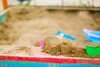 A close-up of a sandpit with toys and a small flower. Podgląd zdjęcia produktu