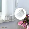 A close-up of a white vertical blind with beaded tassels, with a small inset showing a detail of the blind's mechanism, and a bouquet of flowers in the foreground. Voir les images du produit
