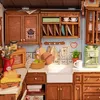 A miniature kitchen scene with cabinets, sink, appliances, and food items. Náhľad obrázku produktu