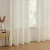 A close-up of sheer beige curtains hanging in front of a window, with a small wooden nightstand and decorative items to the left. Produktbild-Vorschau