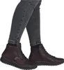 A person wearing dark jeans and brown ankle boots. Produktbild-Vorschau
